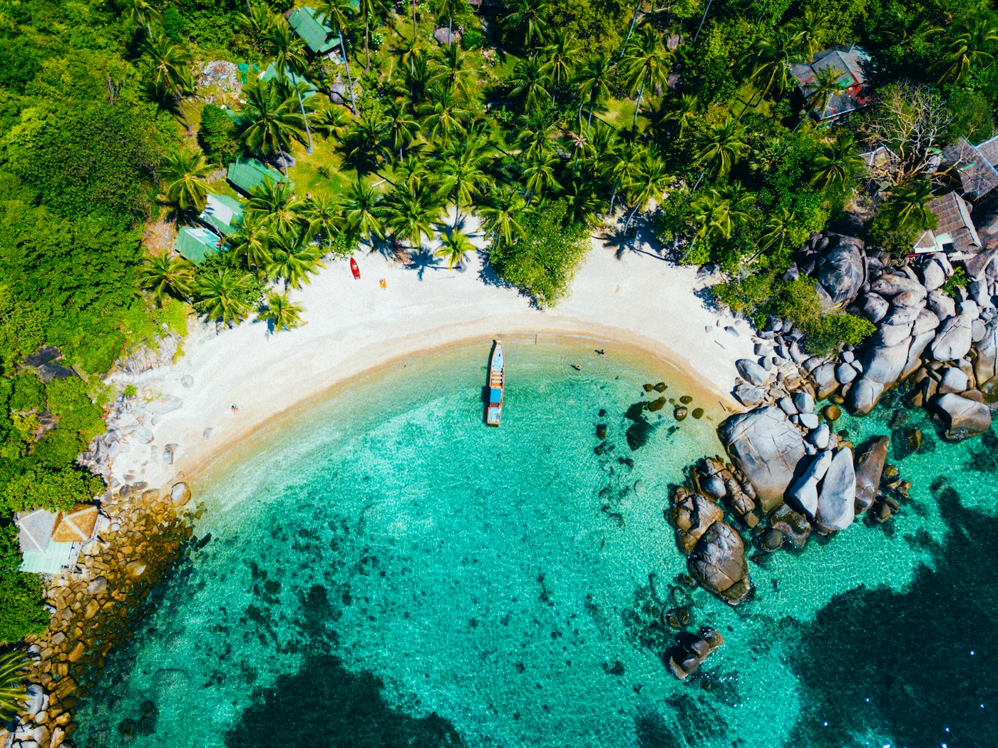 ชายหาดเกาะเต่าสีฟ้าใส ล้อมรอบด้วยต้นมะพร้าวและหิน