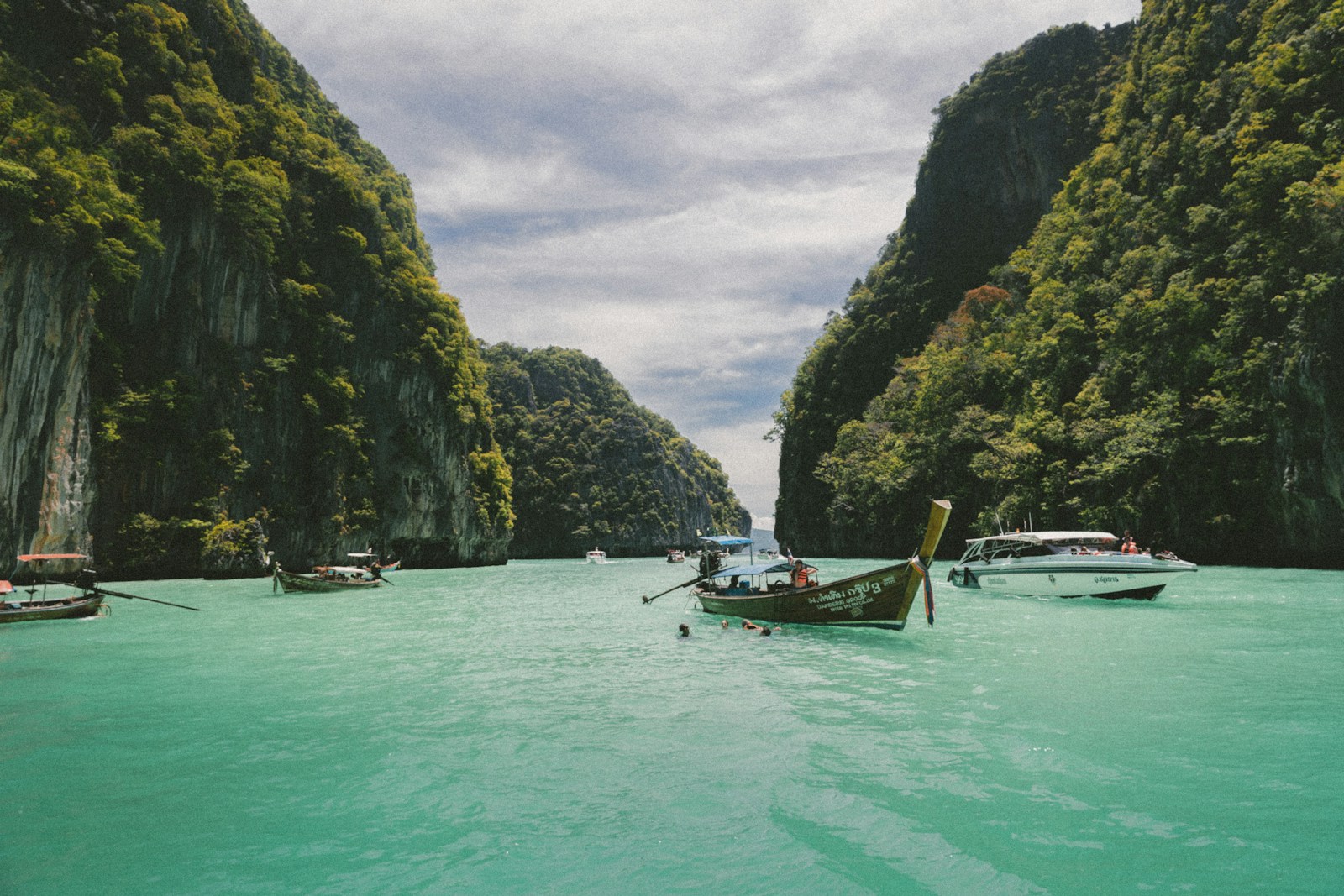 เรือหางยาวลอยอยู่บนน้ำสีมรกต ท่ามกลางภูเขาหินปูนหมู่เกาะพีพี